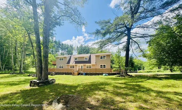 a view of a white house with a big yard and large trees