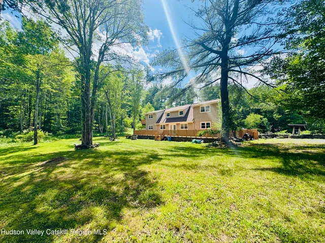 a view of a house with a big yard and large trees