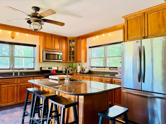 a kitchen with stainless steel appliances granite countertop a sink a stove cabinets dining table and chairs