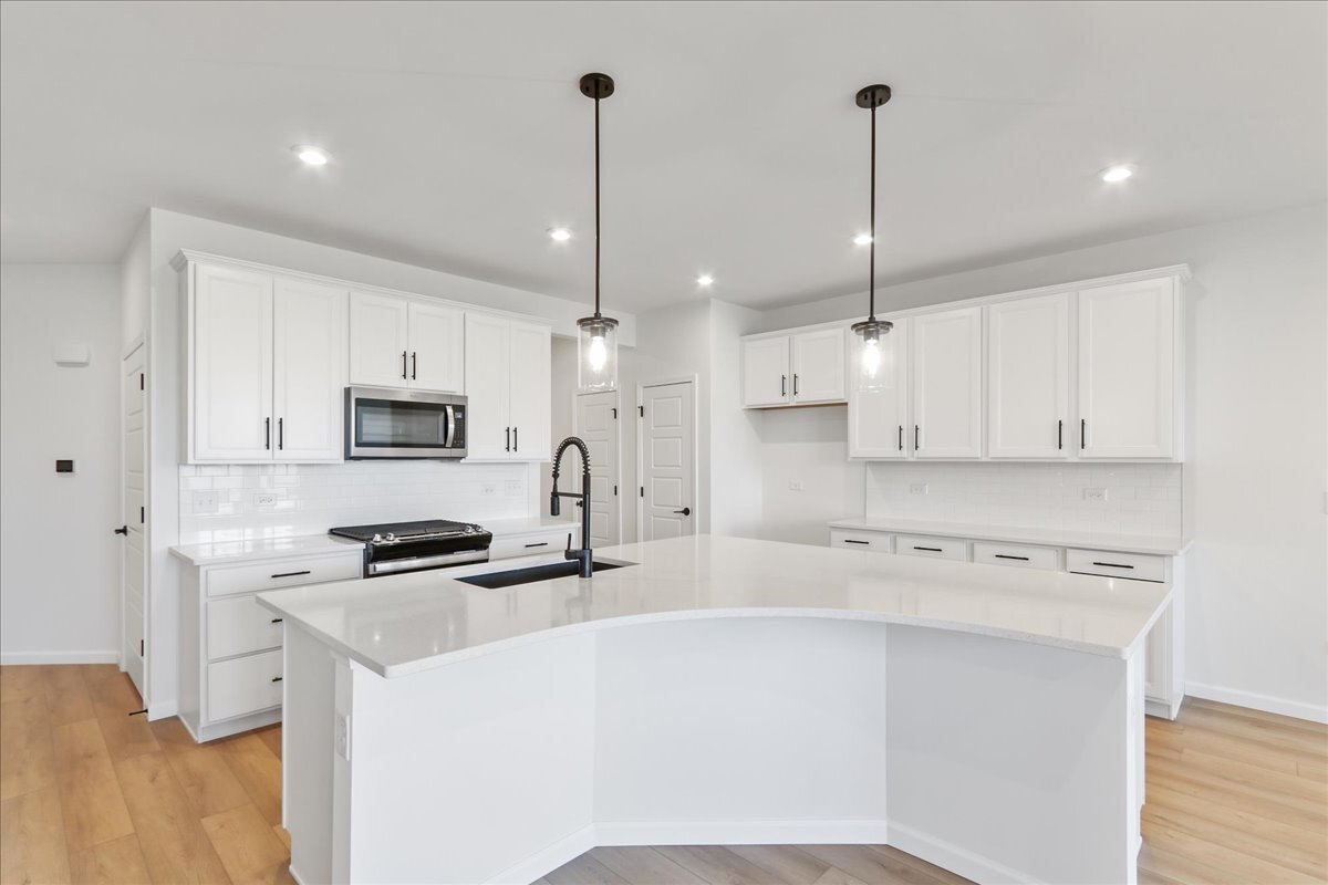 2216 Ryegrass Lane, Unit 78002 Bolingbrook, IL 60490 - Photo 6 of 29 a kitchen with stainless steel appliances white cabinets a sink a stove and a wooden floors