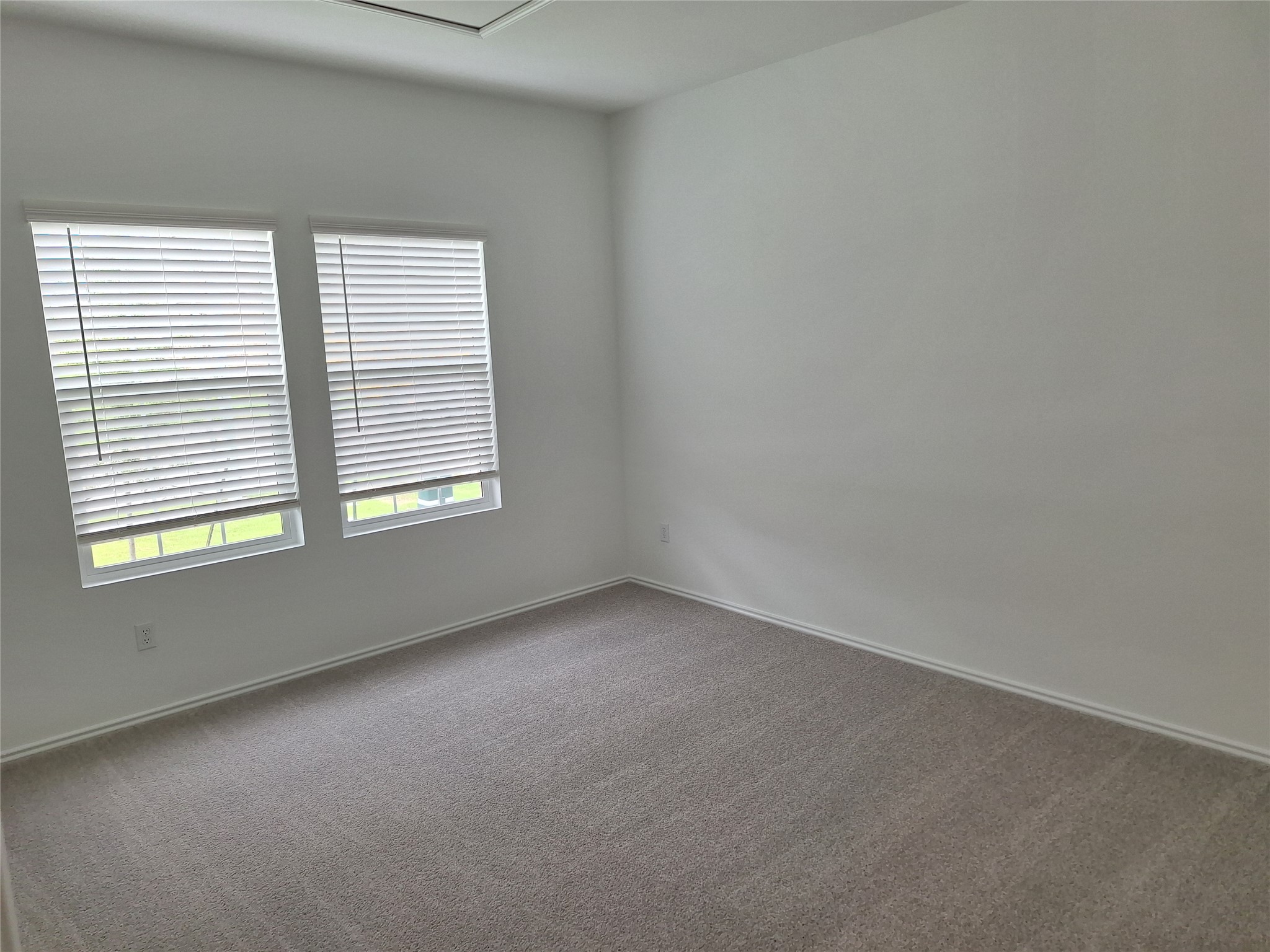 18001 Prairie Falcon Way Pflugerville, TX 78660 - Photo 16 of 38 Room featuring two windows with horizontal blinds, light-colored carpeting, white walls, white trim, and a high ceiling