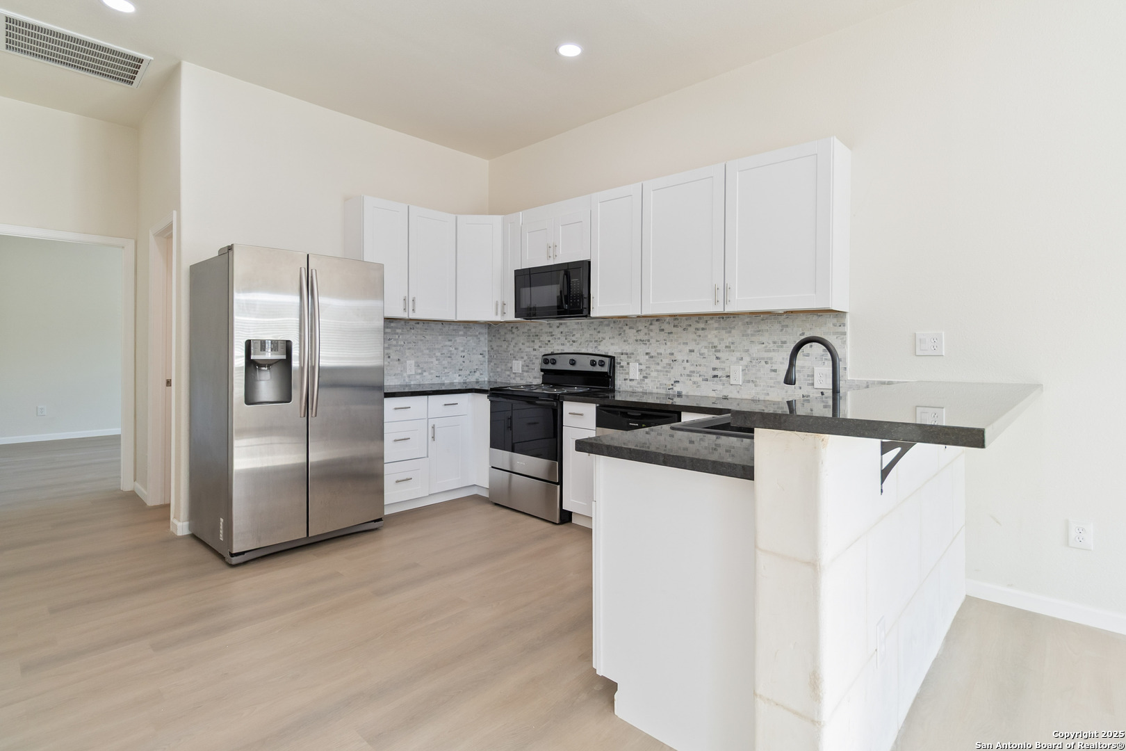 324 Ridgerock Drive, Unit 1 Canyon Lake, TX 78133 - Photo 2 of 21 a kitchen with granite countertop a refrigerator and a stove top oven