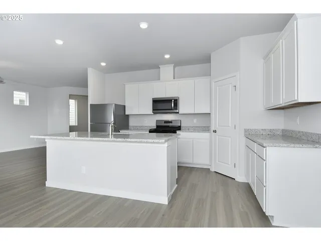 a kitchen with stainless steel appliances granite countertop a stove a sink a refrigerator and white cabinets