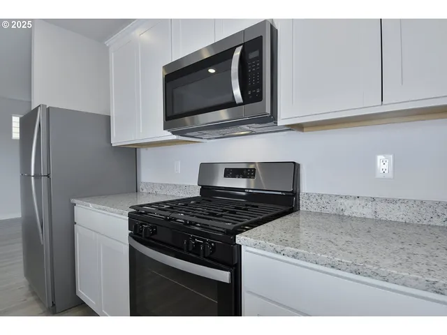 a kitchen with stainless steel appliances granite countertop a stove microwave and refrigerator