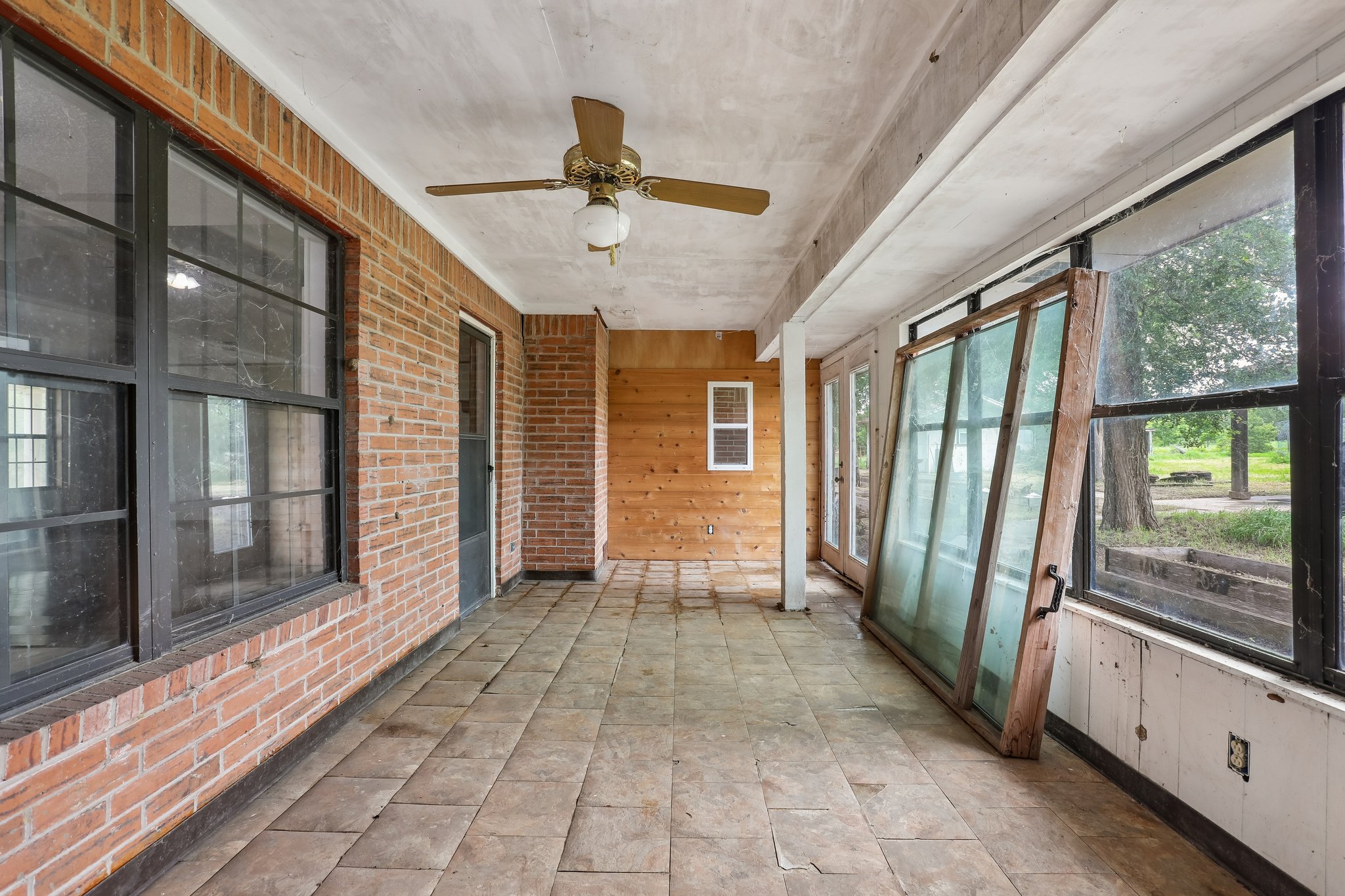 406 Monkey Road Elgin, TX 78621 - Photo 25 of 39 Enclosed porch featuring a brick wall, paneled wood wall, tile flooring, and a ceiling fan with integrated lighting