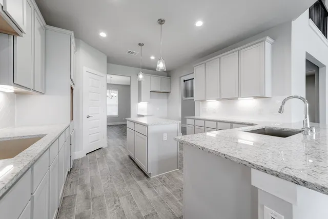 a kitchen with granite countertop a sink and white cabinets