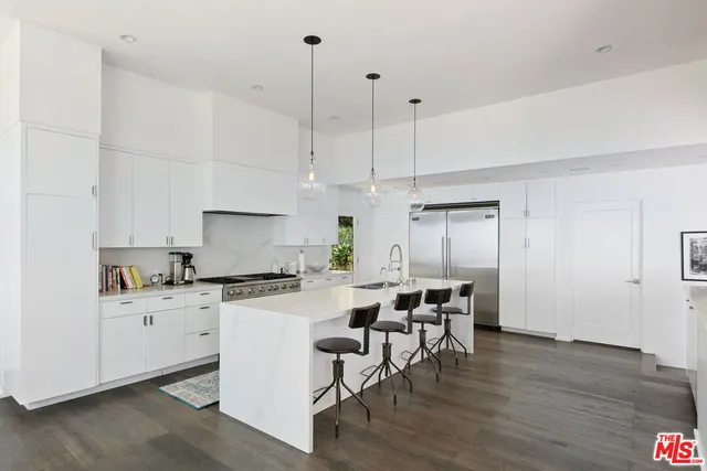 a view of a dining room with furniture a chandelier and large windows