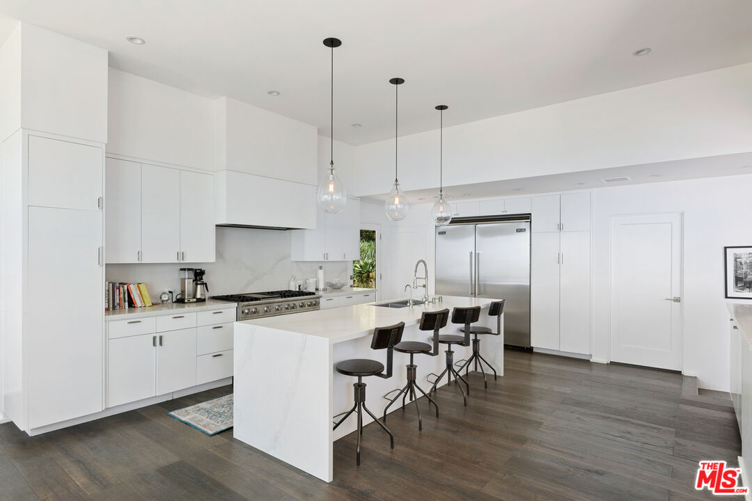 27450 Calicut Road Malibu, CA 90265 - Photo 21 of 59 a kitchen with stainless steel appliances kitchen island a wooden floor and white cabinets