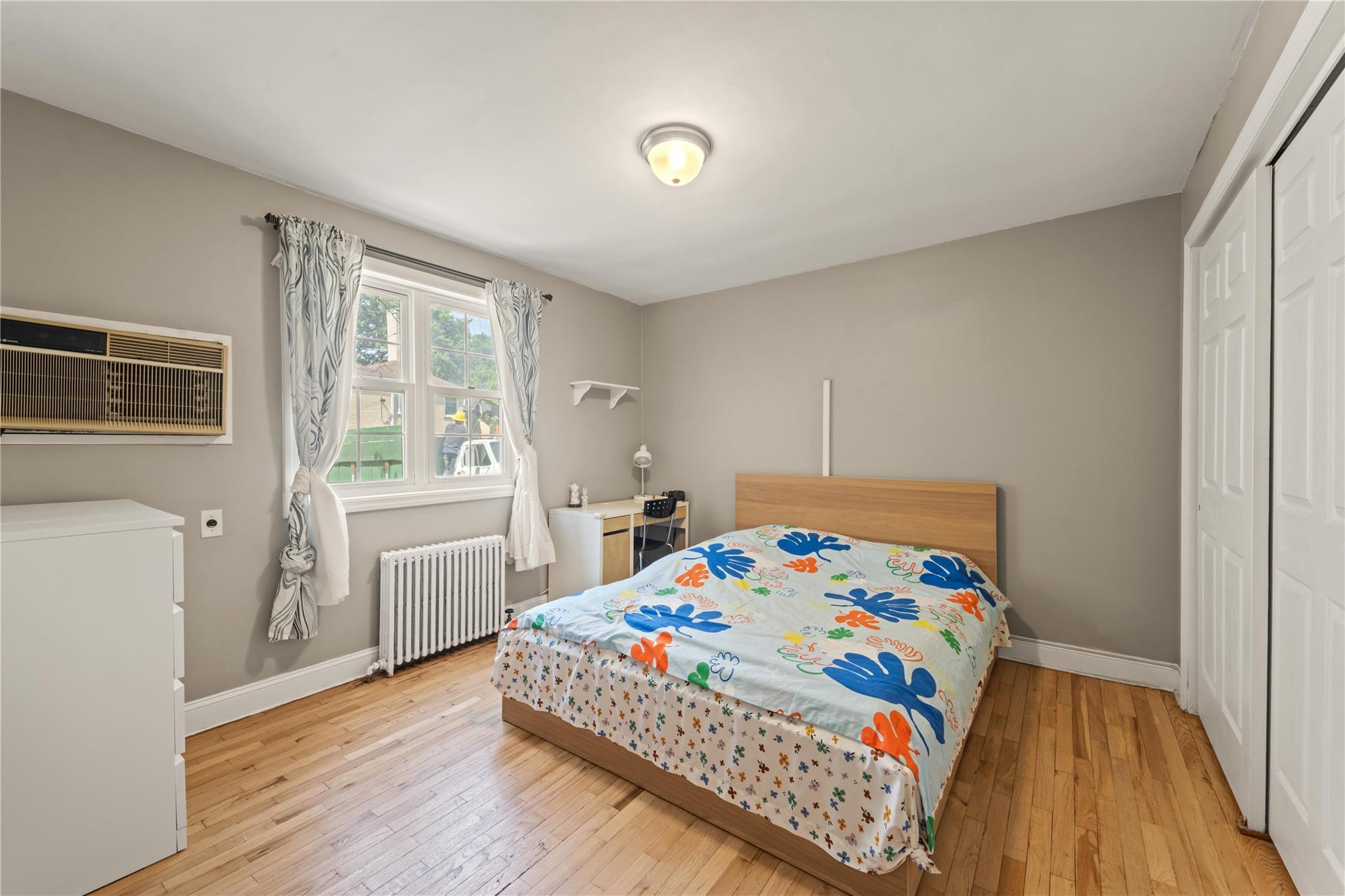 221-03 67th Avenue, Unit 1 Queens, NY 11364 - Photo 7 of 14 a bedroom with a bed and wooden floor