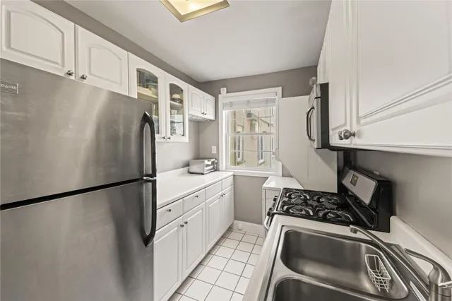 a kitchen with stainless steel appliances granite countertop a refrigerator sink and white cabinets