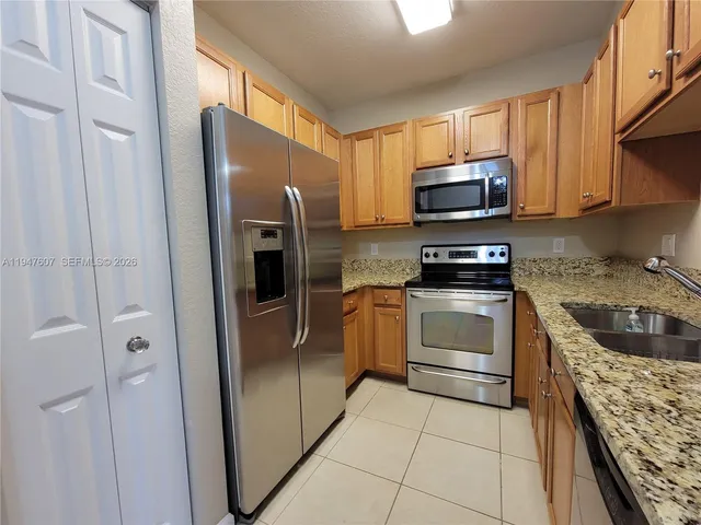 a kitchen with stainless steel appliances granite countertop a refrigerator stove and sink