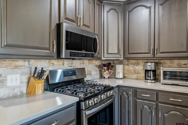 a kitchen with granite countertop a stove a sink and a microwave
