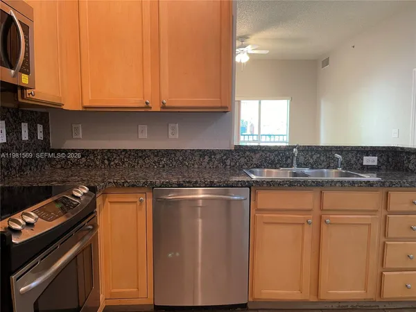 a kitchen with granite countertop white cabinets stainless steel appliances and a sink