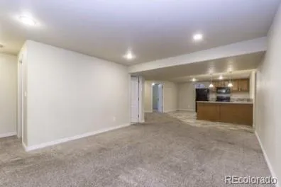 a view of an empty room and a kitchen
