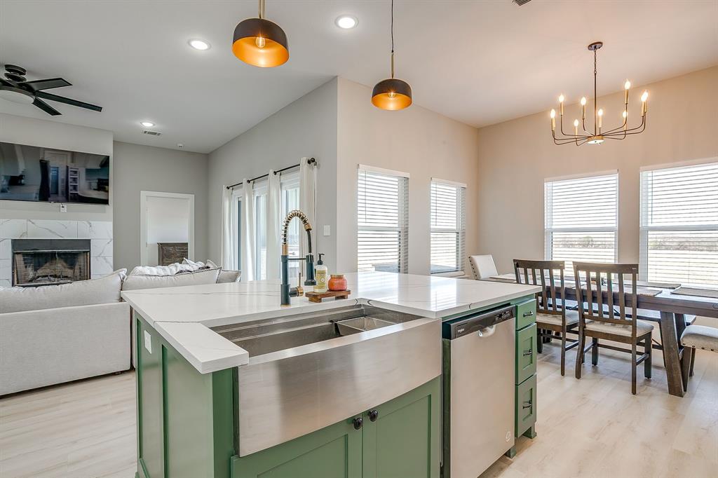 a kitchen with a sink a stove a dining table and chairs with wooden floor