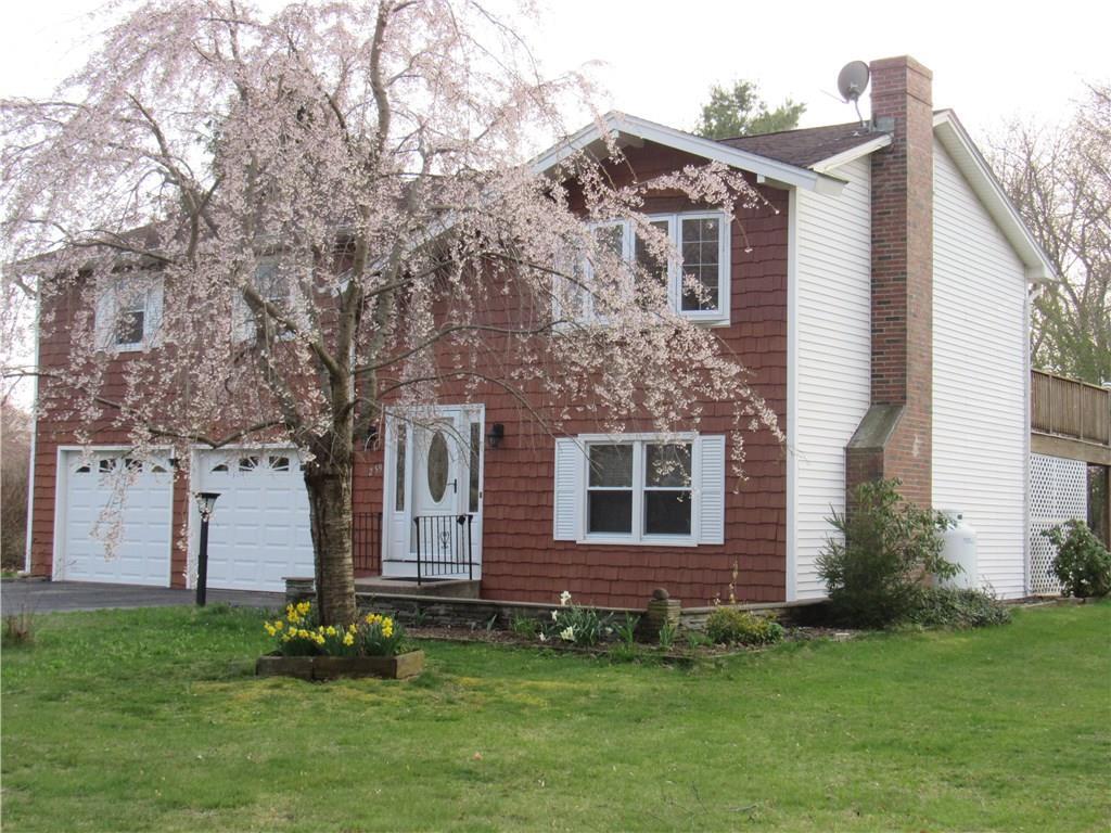 a brick house with a yard plants and large trees