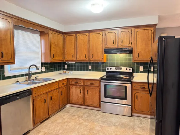 a kitchen with stainless steel appliances granite countertop a sink a stove a refrigerator and cabinets