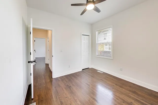 an empty room with wooden floor fan and windows