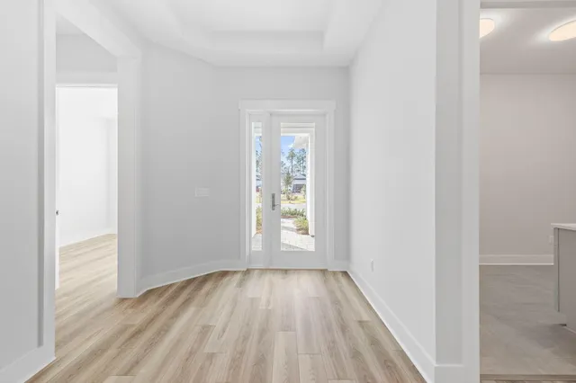 a view of an empty room with wooden floor and window