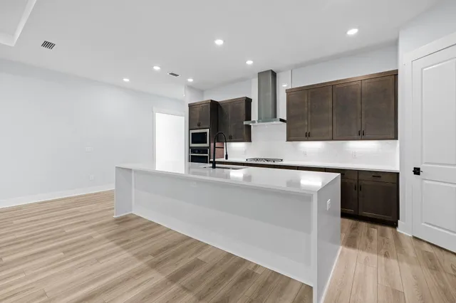 a large white kitchen with kitchen island a sink stainless steel appliances and cabinets