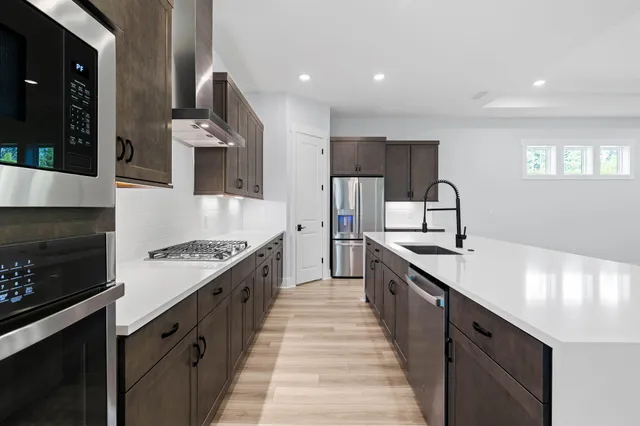a large kitchen with stainless steel appliances granite countertop a lot of counter space and wooden floor