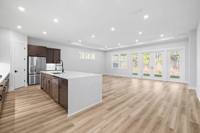 a large kitchen with stainless steel appliances granite countertop a large counter top and wooden floors
