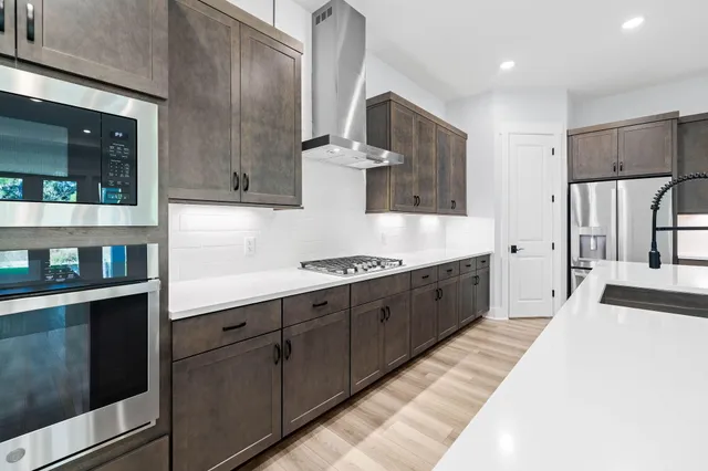 a large kitchen with a large counter top stainless steel appliances and cabinets