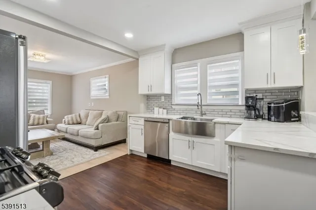 a large white kitchen with a stove a sink a refrigerator and white cabinets with wooden floor