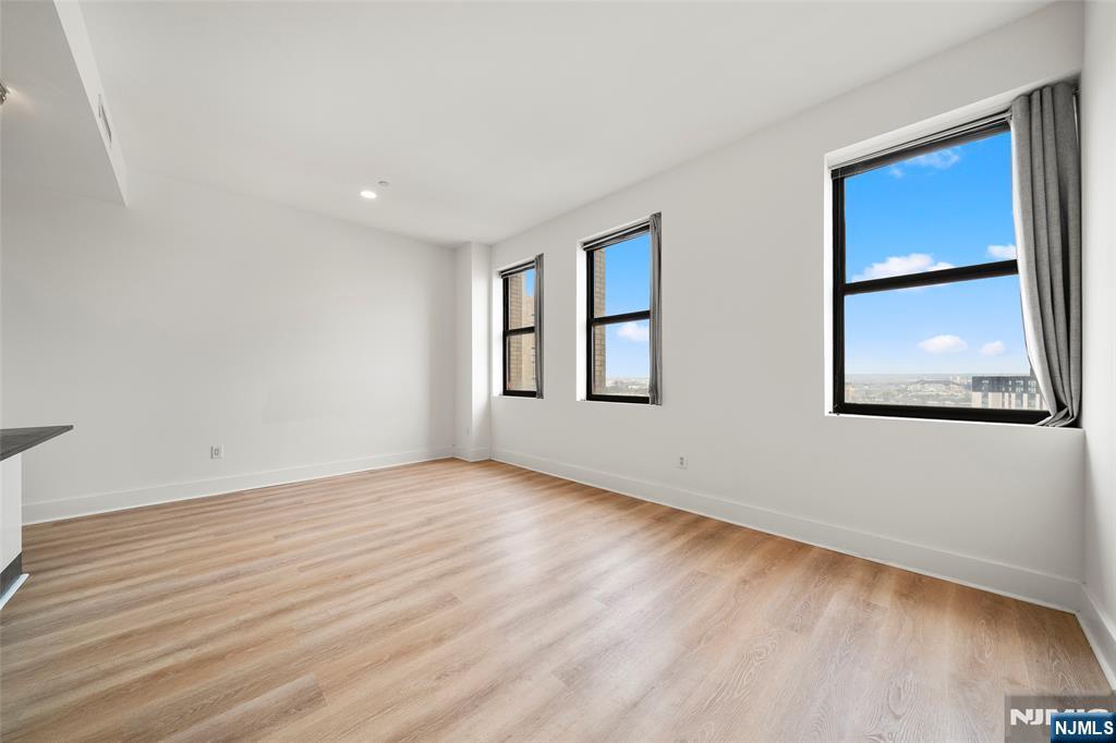 4 Beacon Way, Unit 1407 Jersey City, NJ 07304 - Photo 7 of 19 a view of an empty room with wooden floor and a window