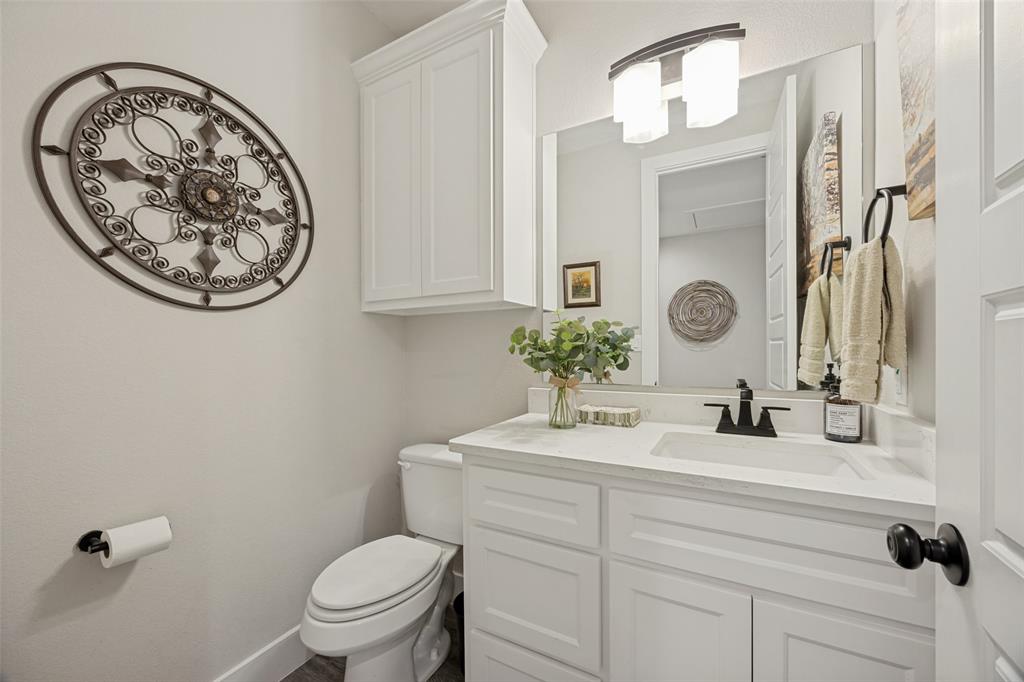 1105 Ranch Drive Bonham, TX 75418 - Photo 14 of 25 Hallway Half Bathroom featuring a white vanity with built-in cabinetry, an undermount sink, a matte black faucet, and a large mirror