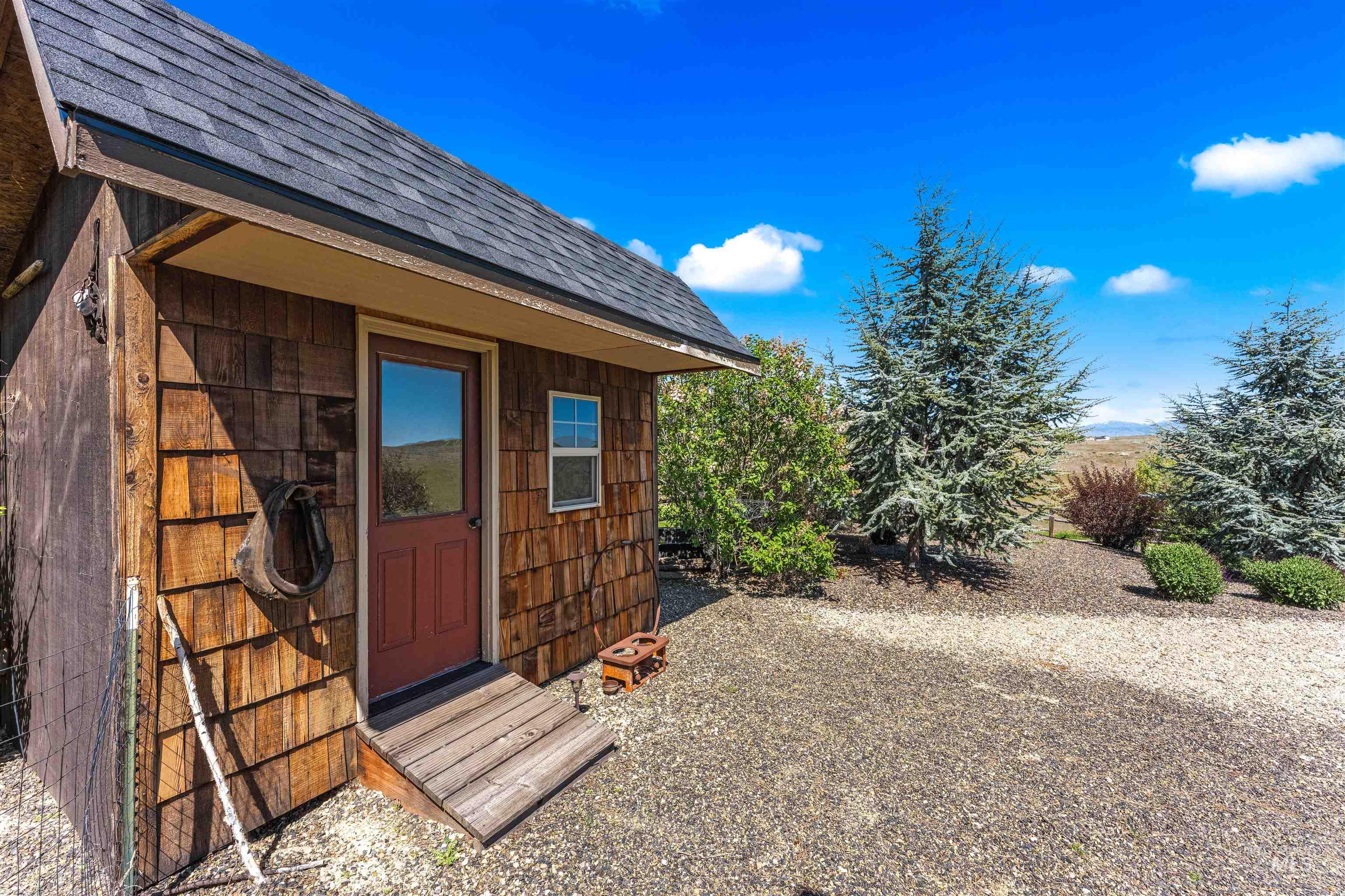 7521 North Grand Ridge Lane Eagle, ID 83616 - Photo 45 of 50 Outbuilding featuring cedar shake siding, an asphalt shingle roof, and a red door with a window
