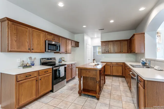 a kitchen with stainless steel appliances granite countertop a stove top oven a sink dishwasher and a refrigerator