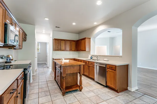 a kitchen that has a sink a stove and chairs in it