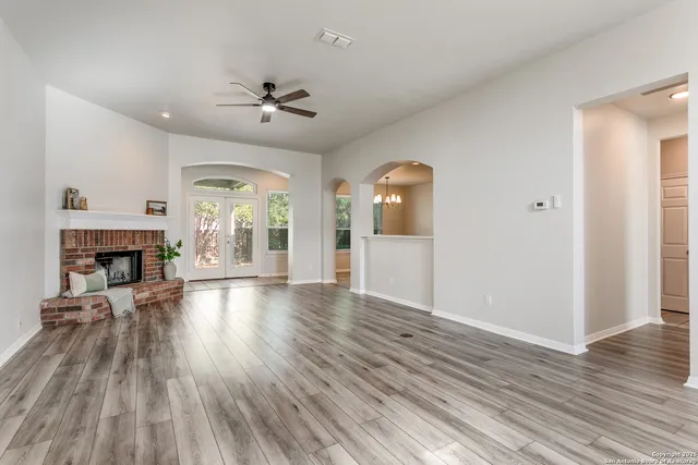 an empty room with wooden floor fireplace and windows