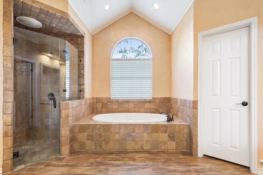 4843 South 3rd St Road Waco, TX 76706 - Photo 23 of 39 Bathroom featuring vaulted ceiling, a bath, a stall shower, and wood finished floors