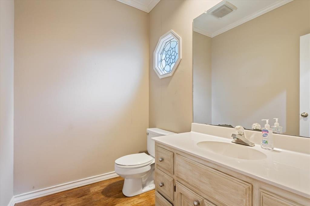 4843 South 3rd St Road Waco, TX 76706 - Photo 28 of 39 Half bathroom with crown molding, wood finished floors, vanity, toilet, and visible vents