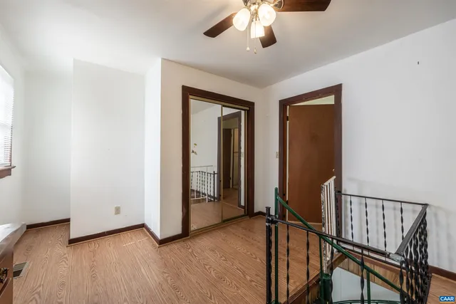 a view of an empty room with windows and chandelier fan