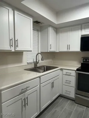 a kitchen with white cabinets appliances and a sink