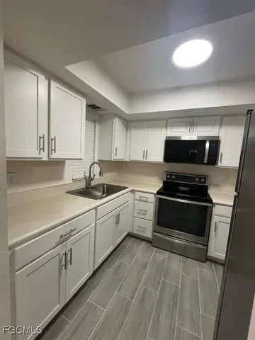 a kitchen with granite countertop a sink cabinets and stainless steel appliances