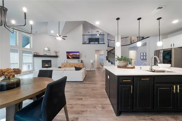 a kitchen with stainless steel appliances granite countertop a sink dishwasher and a dining table with wooden floor