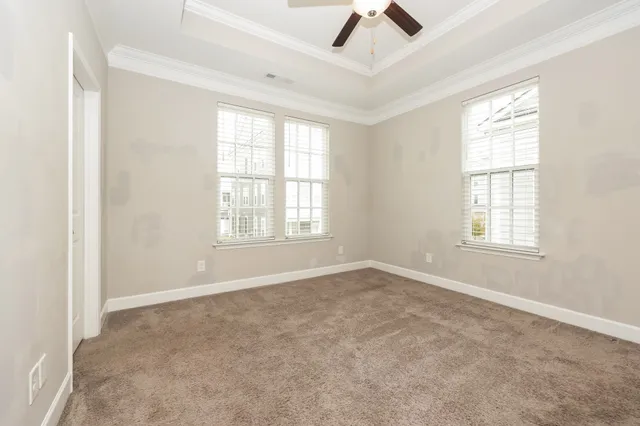 an empty room with ceiling fan and windows