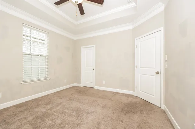 an empty room with chandelier fan and windows