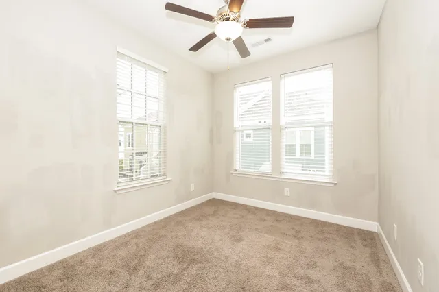 an empty room with windows and fan