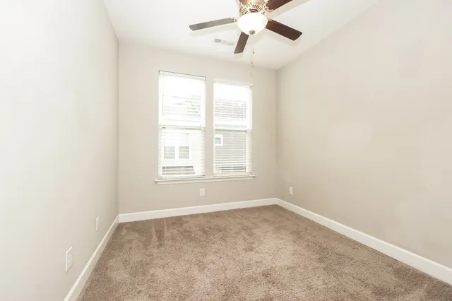 an empty room with a window and a fan