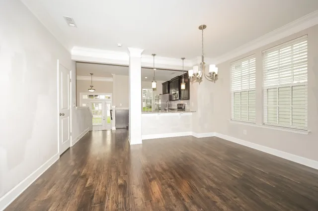 a view of a hallway with wooden floor and a kitchen