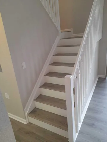 a view of staircase with wooden floor and white walls