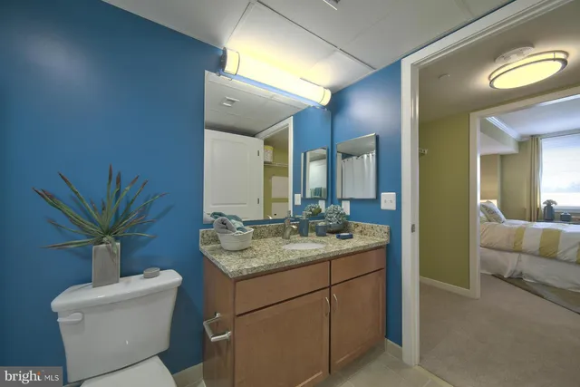 a bathroom with a granite countertop sink a toilet and a mirror