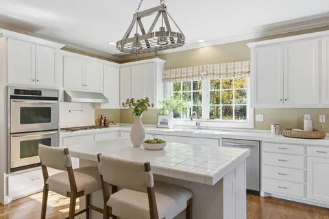 a kitchen with granite countertop white cabinets and stainless steel appliances