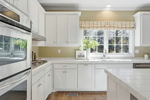 a kitchen with stainless steel appliances granite countertop a sink and a white cabinets
