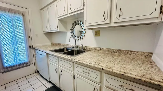 a kitchen with white cabinets and sink